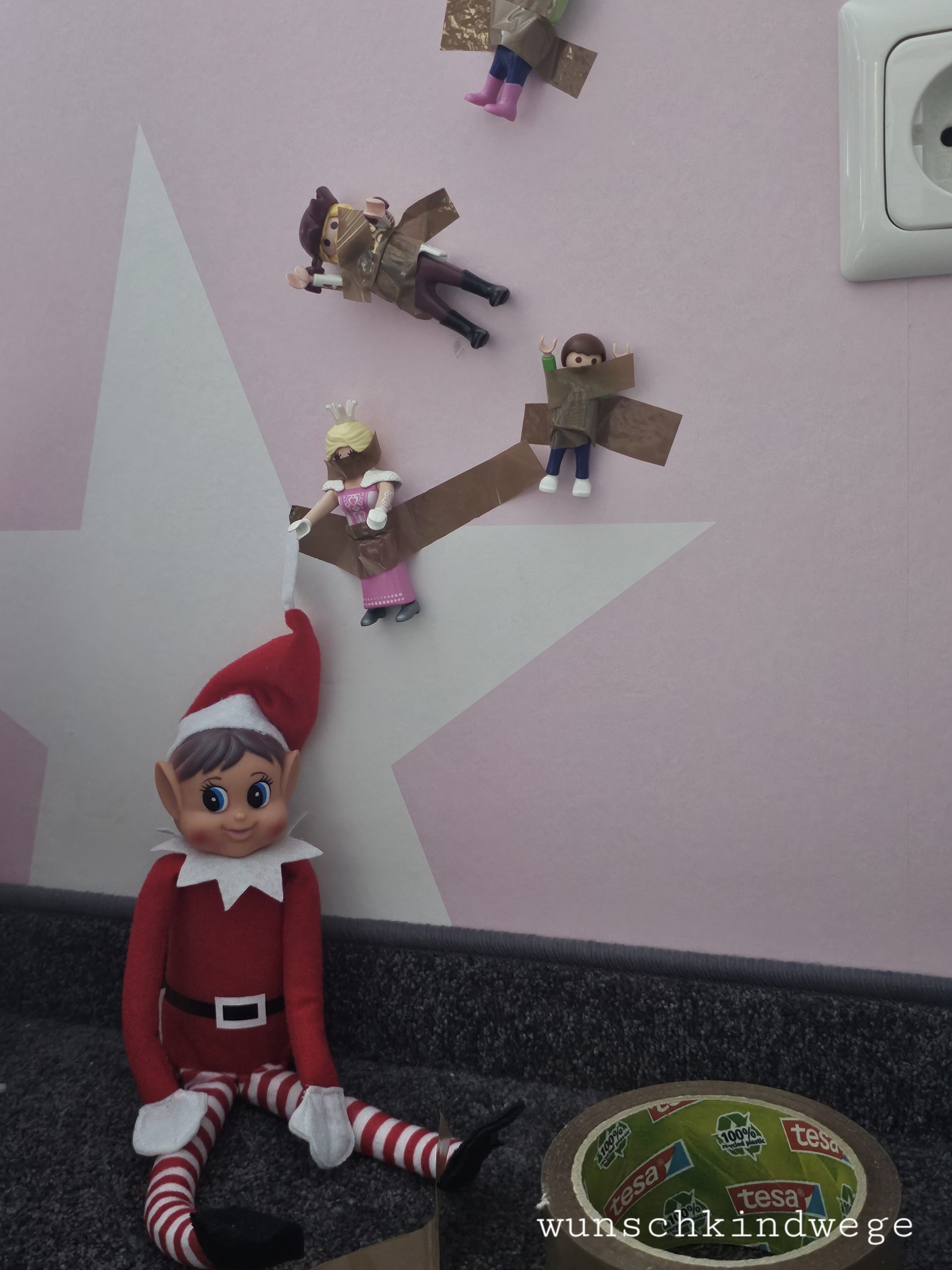 Elf on the Shelf an die Wand getaped